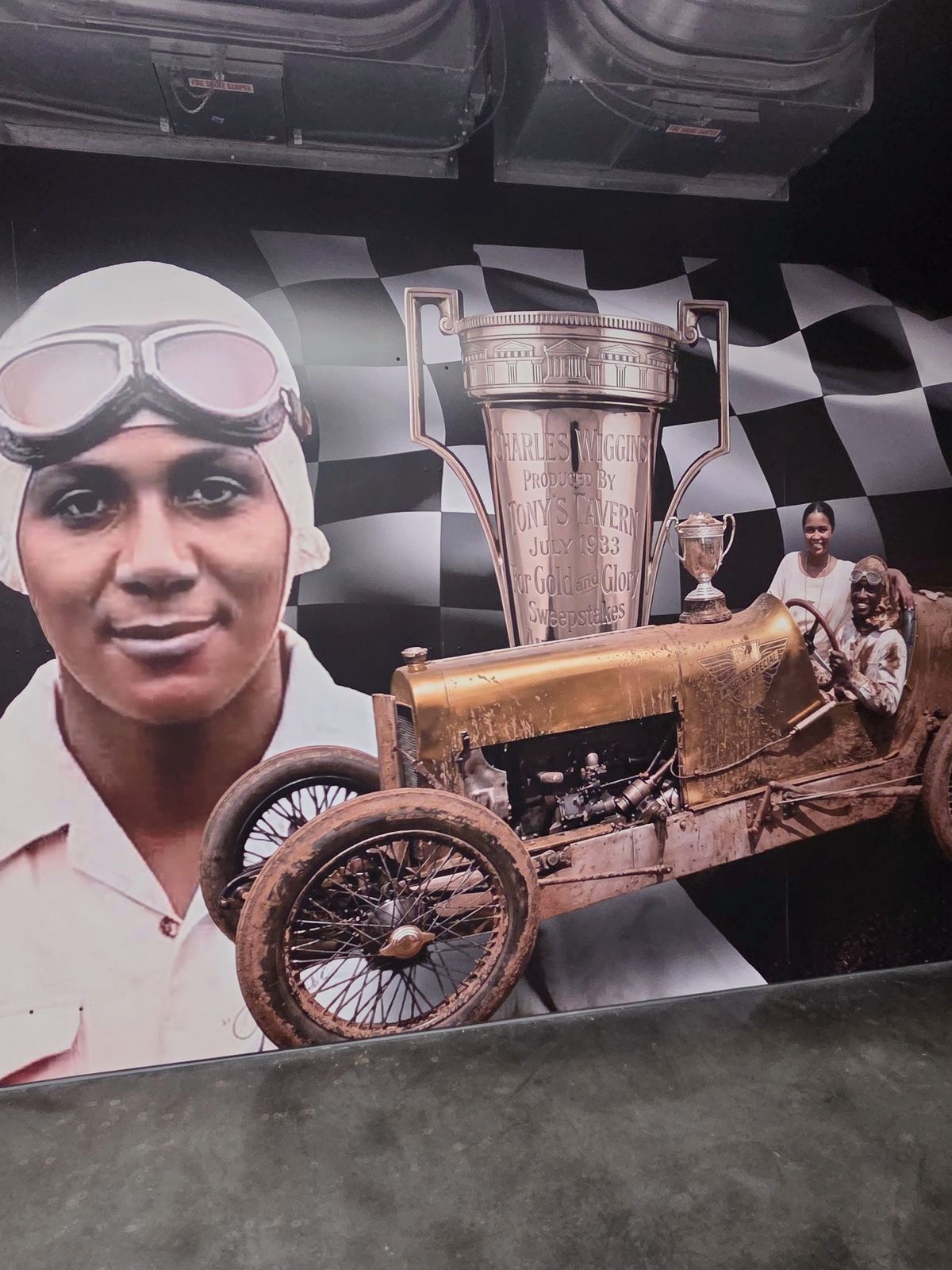 Charlie Wiggins, in goggles, beside his race car.